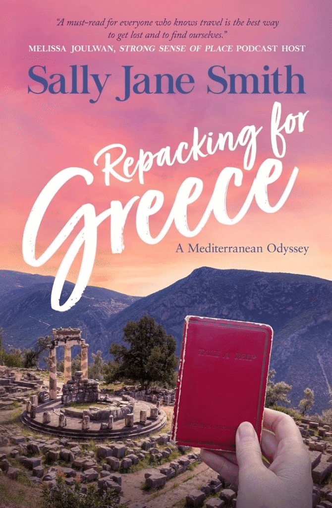 Book cover image of a close up of a hand holding a red cover book in the foreground of an ancient Greek ruin in the mountains, the book's title is Repacking for Greece, A Mediterranean Odyssey by Sally Jane Smith